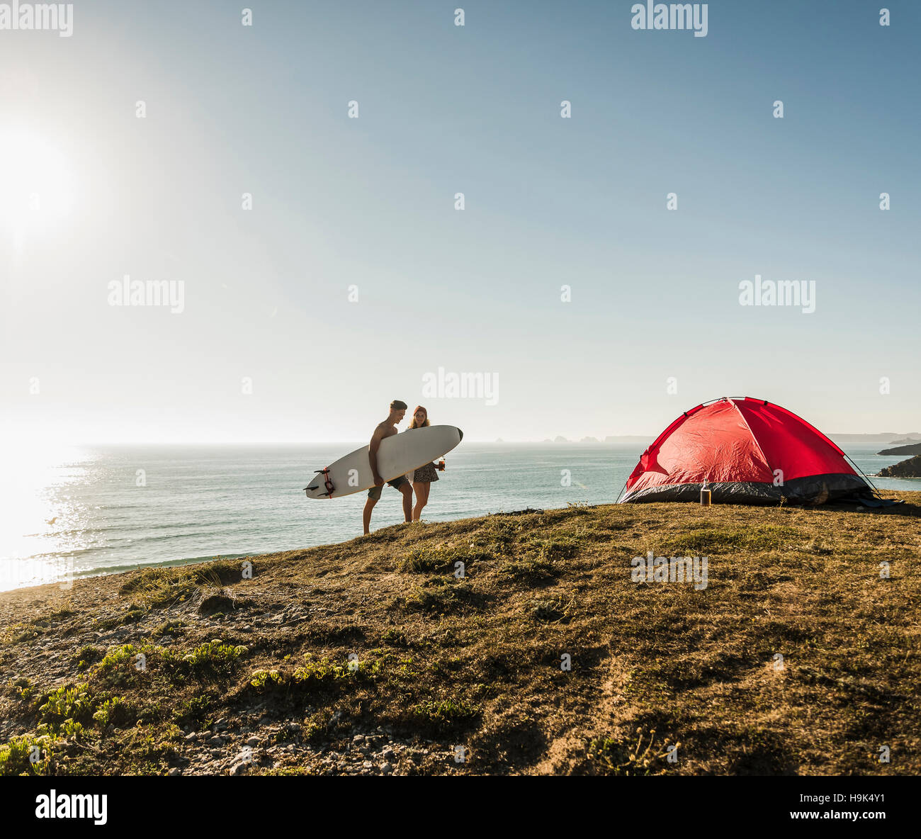 Young couple with surfboard camping at seaside Stock Photo