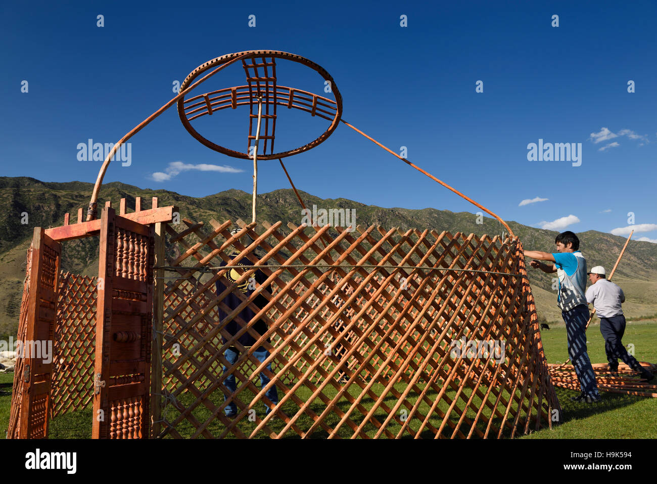 Three men setting up a yurt frame in pasture of Chilik river valley Saty Kazakhstan Stock Photo