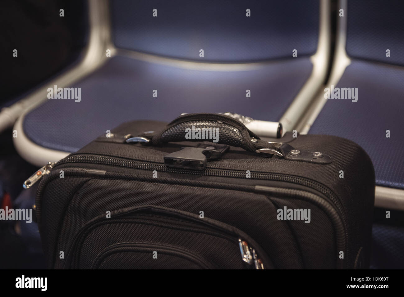 Black color trolley travel bag against seats Stock Photo