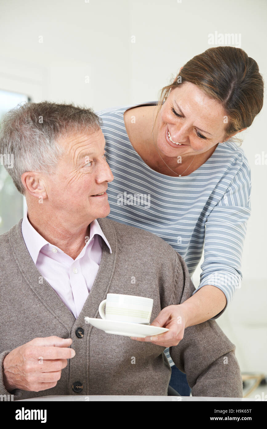 Adult Daughter Bringing Senior Father Hot Drink At Home Stock Photo