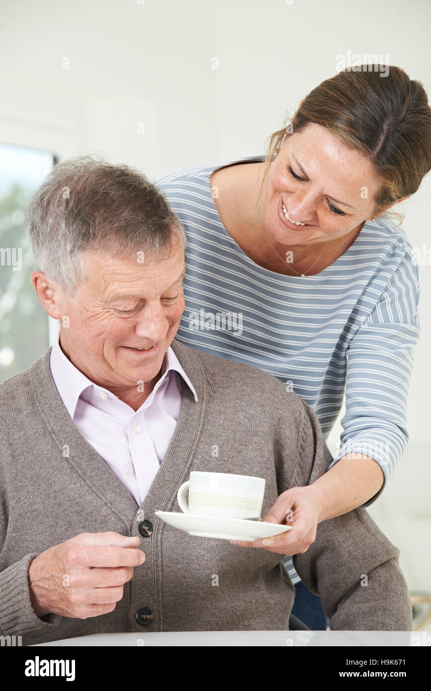 Adult Daughter Bringing Senior Father Hot Drink At Home Stock Photo