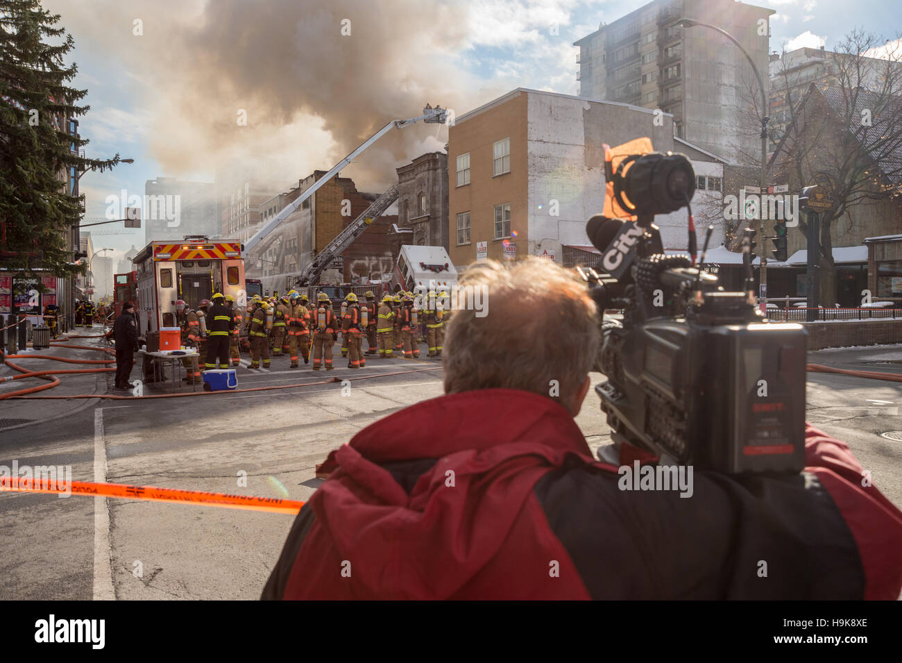 Montreal, CA - 23 Nov 2016: A cameraman is filming firefighters working on 'Cafe Amusement 68' building on fire, 3464 Park Avenue. Stock Photo
