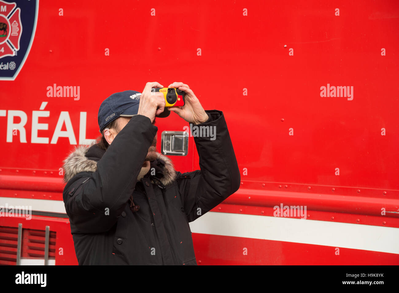 Montreal, CA - 23 Nov 2016: A man is taking pictures of a fire, with a disposable camera, in front of a firetruck Stock Photo