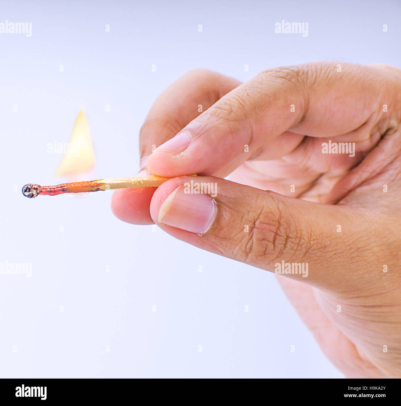 Hand holding a fired matchstick on a white background Stock Photo