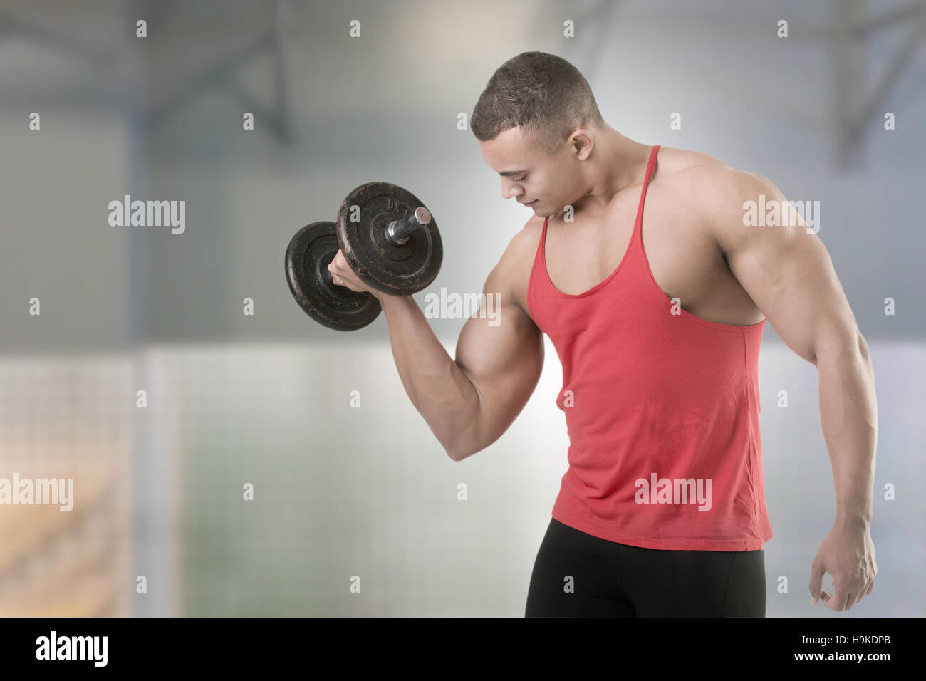 Fit athlete doing standing dumbbell curls for training his biceps, isolated in white Stock Photo