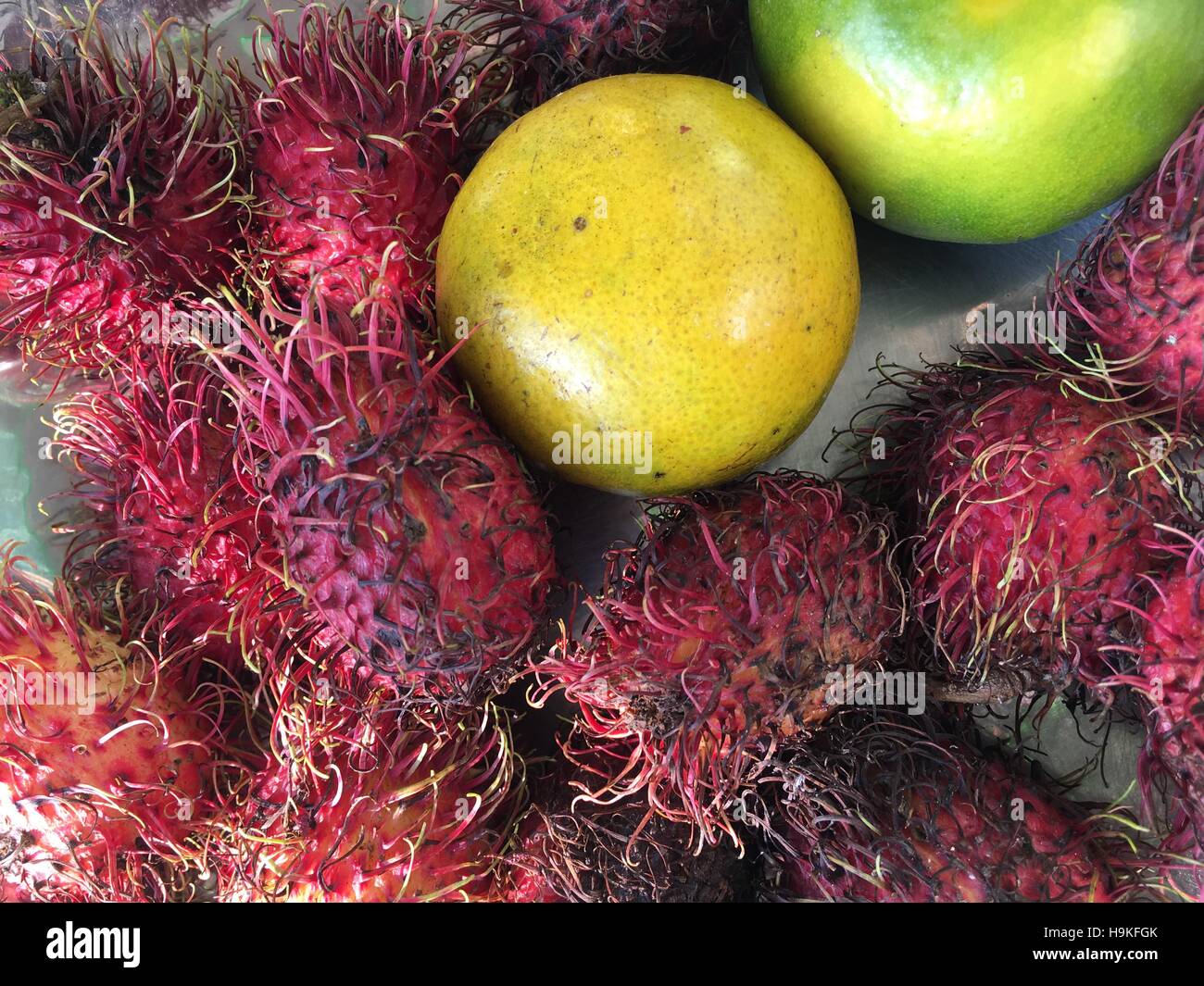 Asian fruits in a plate on a table : Lychee, Lemon , Lime. Round and hairy fruit. Lychees Stock Photo