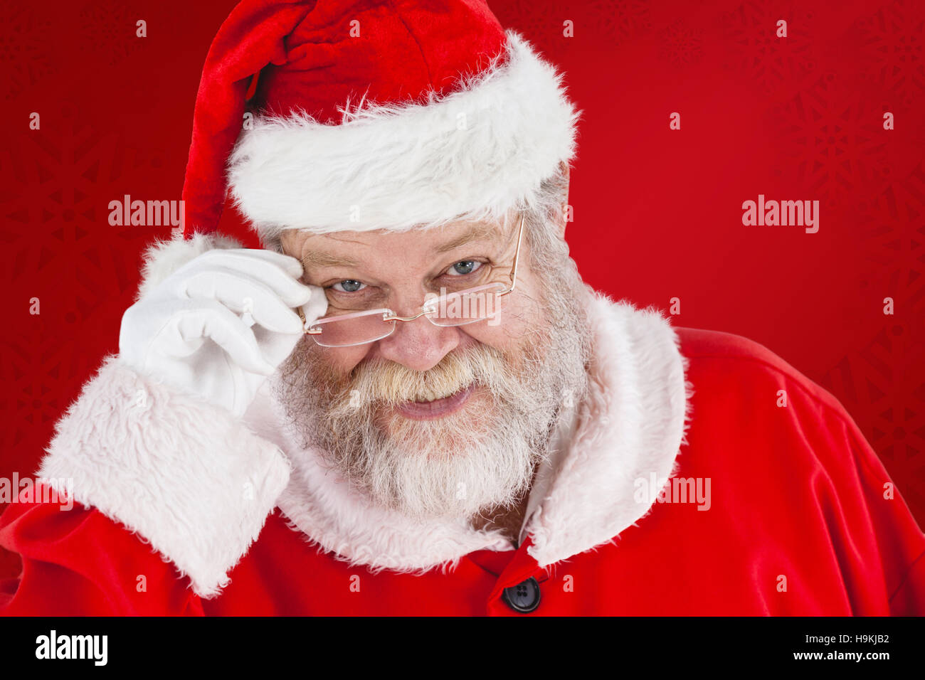 Composite image of santa claus holding spectacles Stock Photo