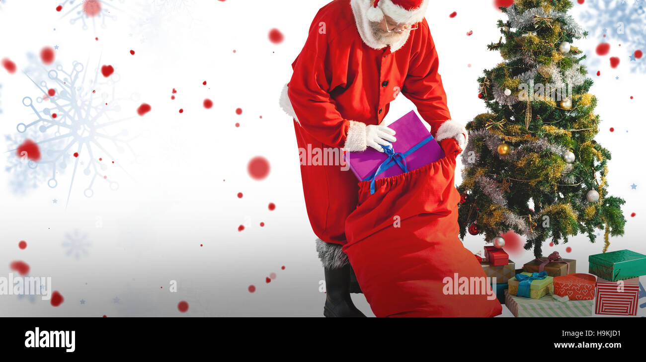 Composite image of santa claus packing christmas bag Stock Photo