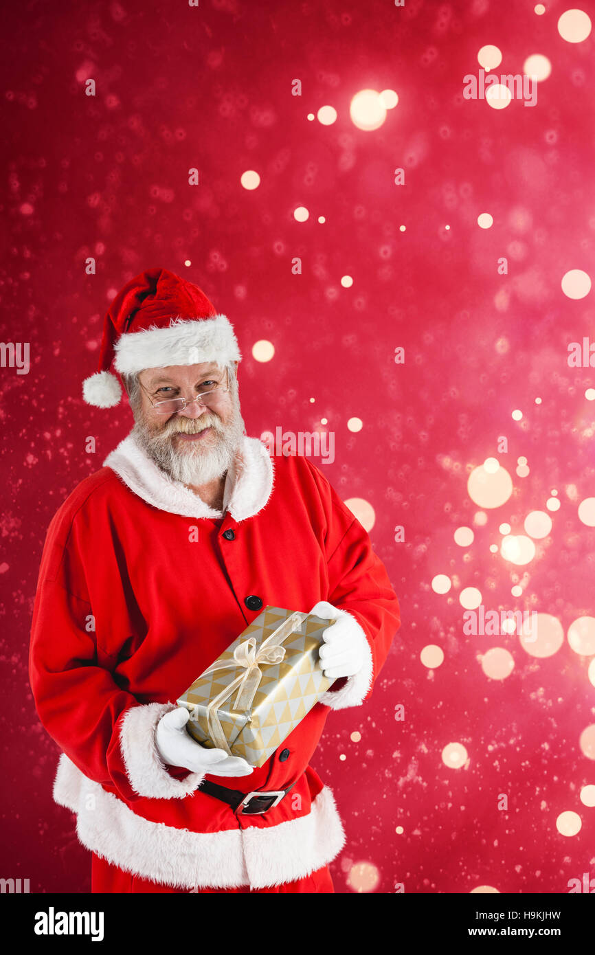 Composite image of portrait of santa claus holding christmas gift box Stock Photo