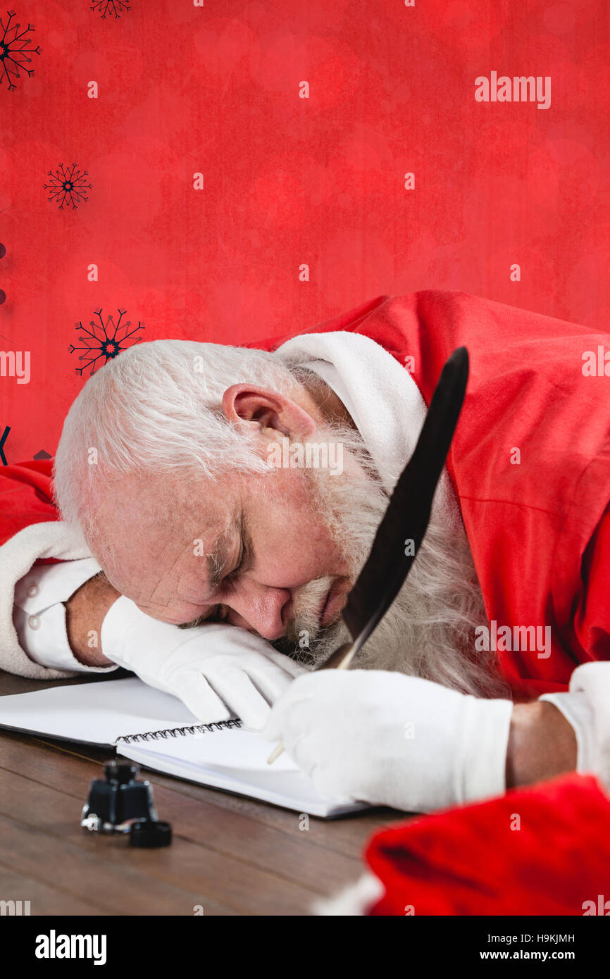 Composite image of santa claus sleeping at desk while writing letter Stock Photo