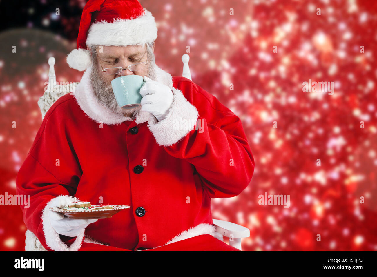 Composite image of santa claus having coffee with cookies Stock Photo