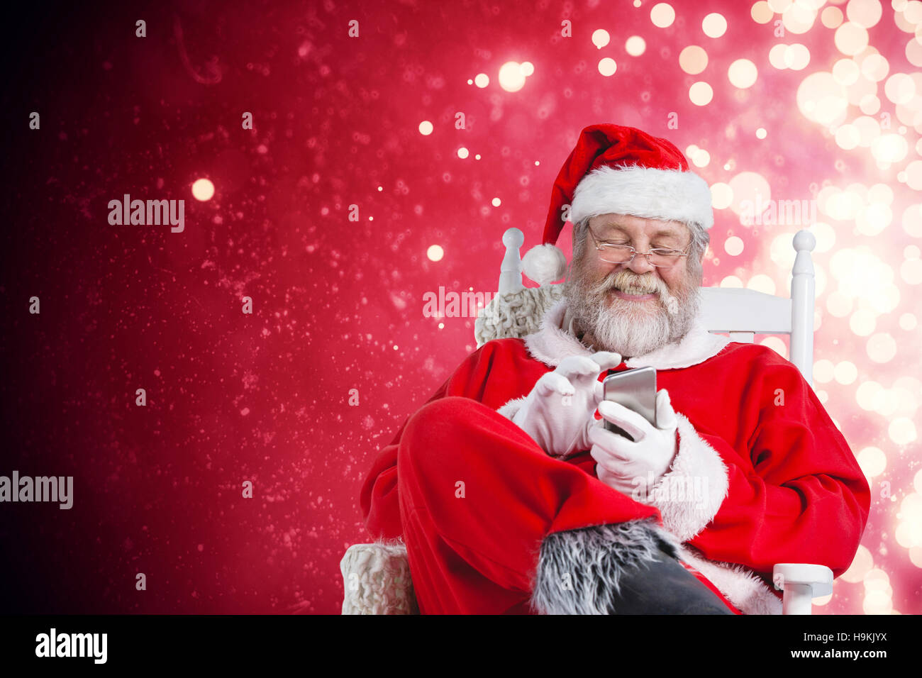 Composite image of happy santa claus messaging with mobile phone Stock Photo