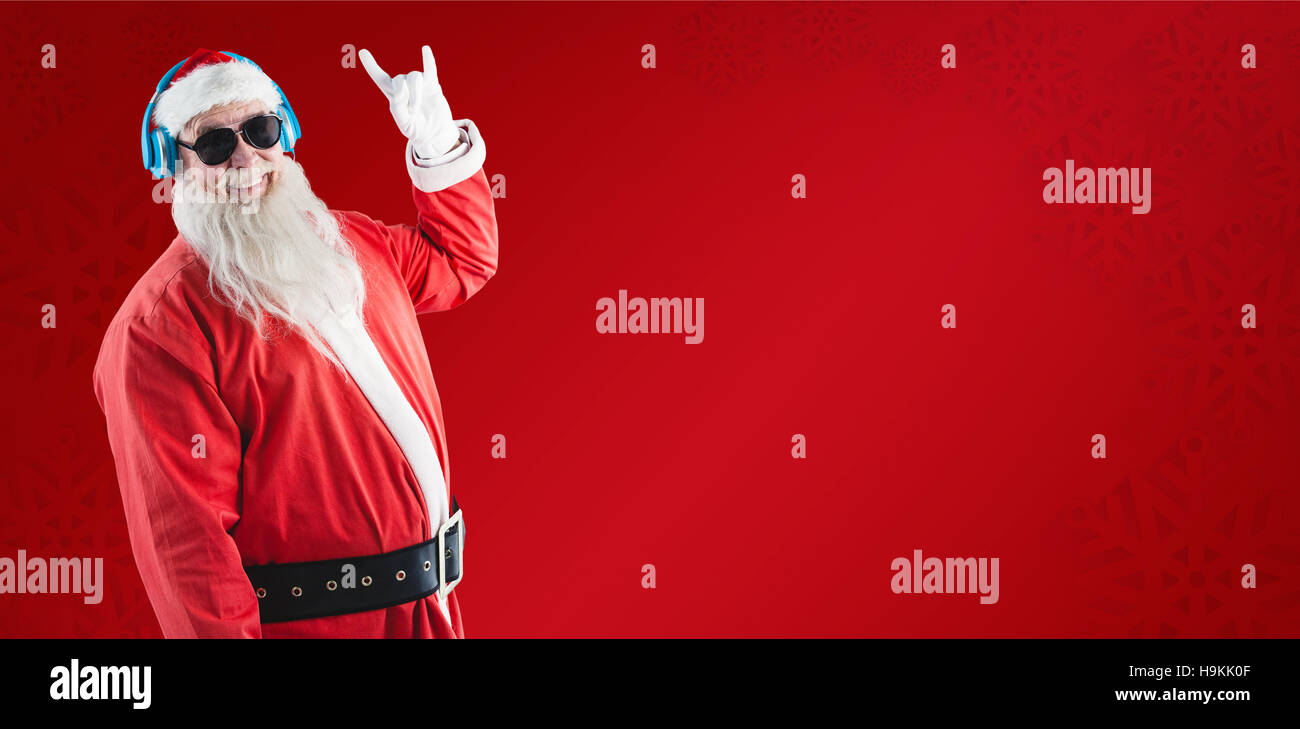 Composite image of santa claus showing hand yo sign while listening to music on headphones Stock Photo