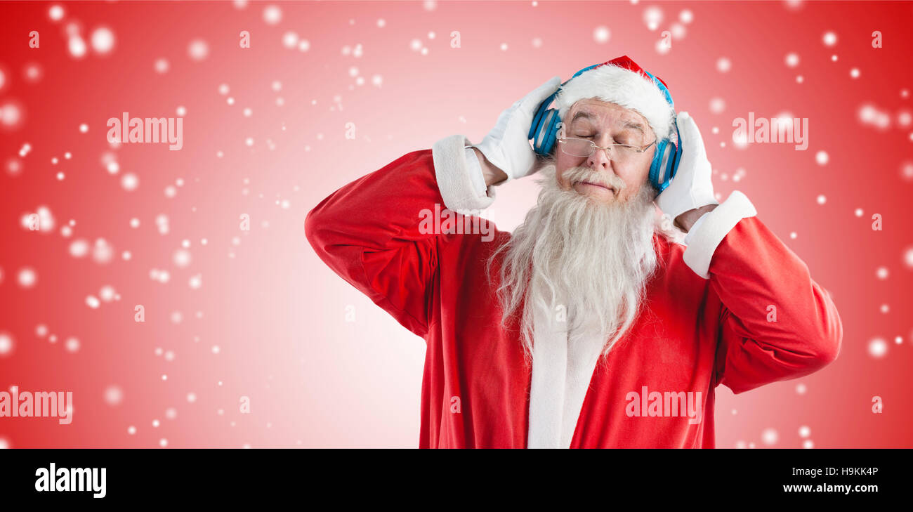Composite image of santa claus listening to music on headphones with eye closed Stock Photo