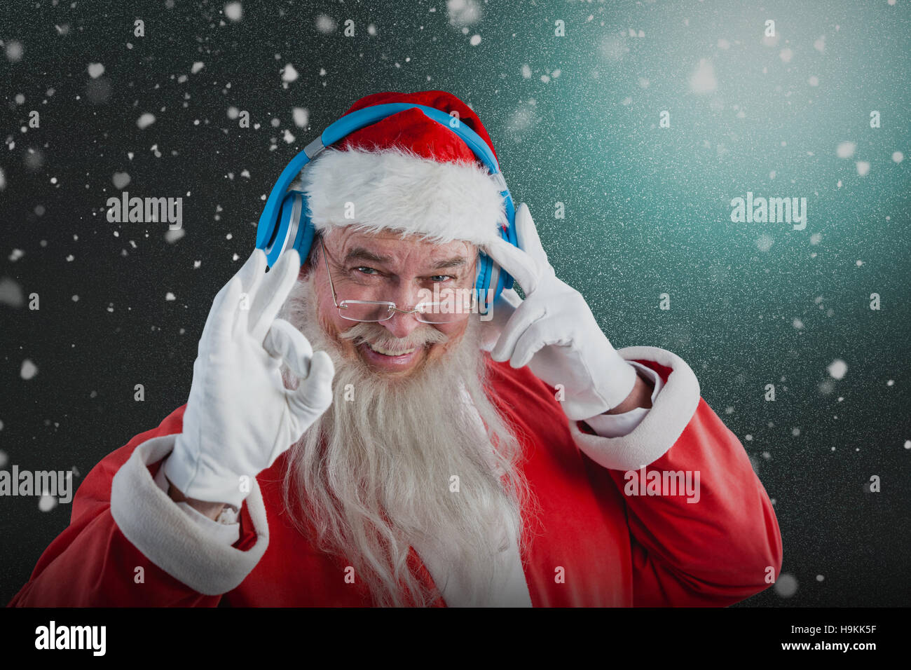 Composite image of portrait of santa claus showing hand okay sign while listening to music on headph Stock Photo