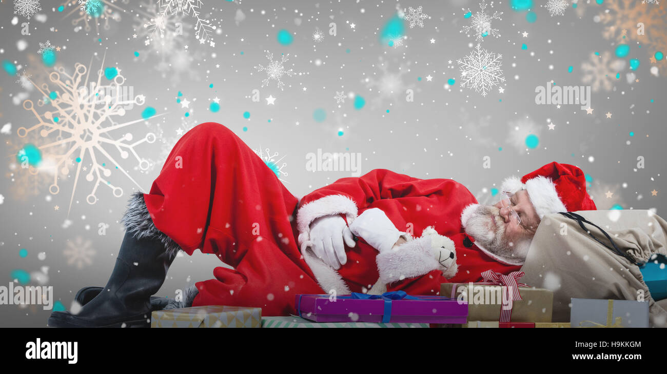 Composite image of santa claus resting beside christmas gifts Stock Photo