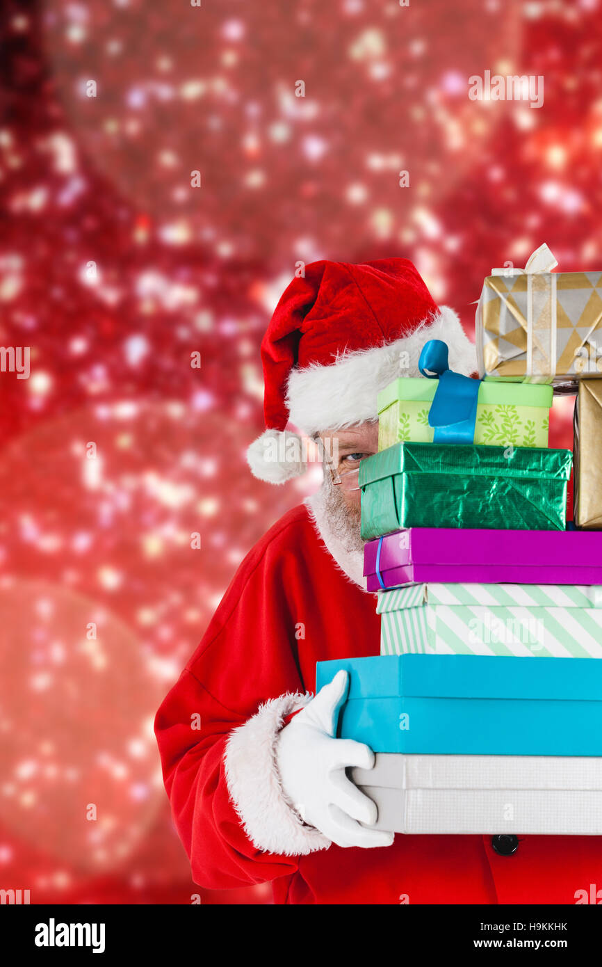 Composite image of santa claus hiding behind stack christmas gifts ...