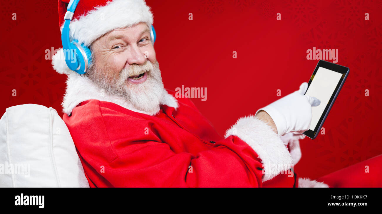 Composite image of portrait of santa claus listening music with digital tablet Stock Photo