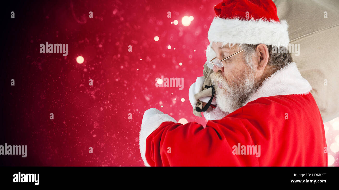 Composite image of santa claus looking at wristwatch Stock Photo