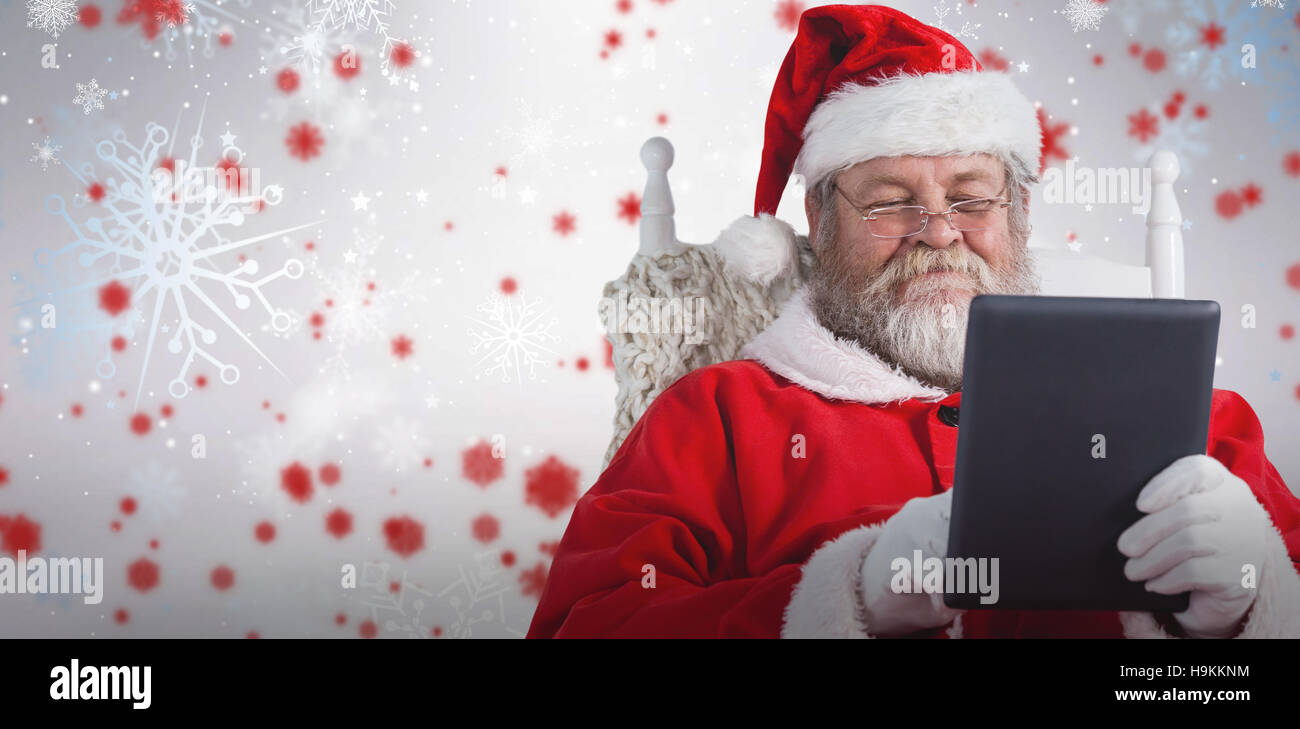 Composite image of close-up of santa claus holding digital tablet on armchair Stock Photo