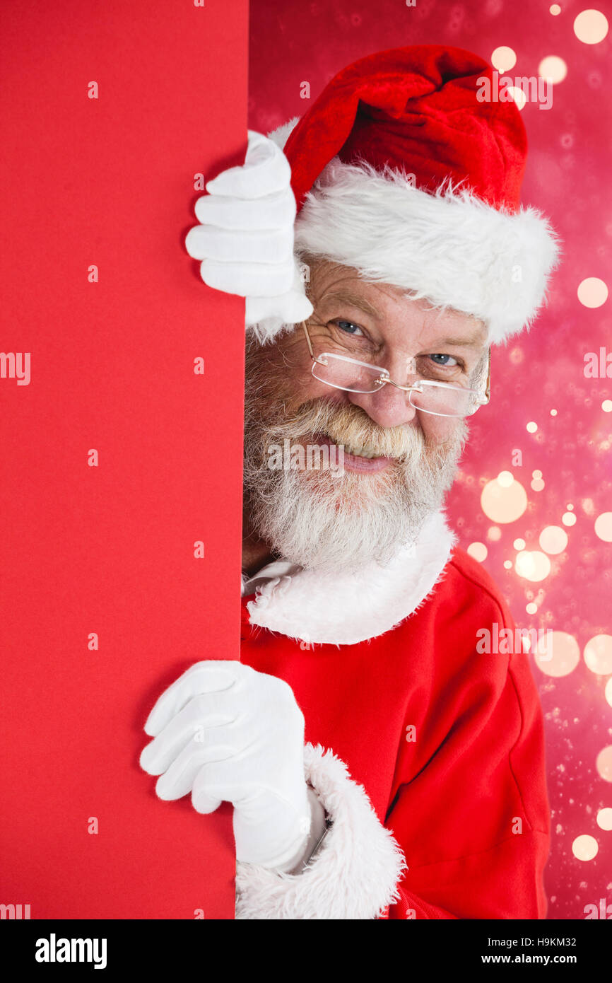 Composite image of santa claus peeking from red board Stock Photo