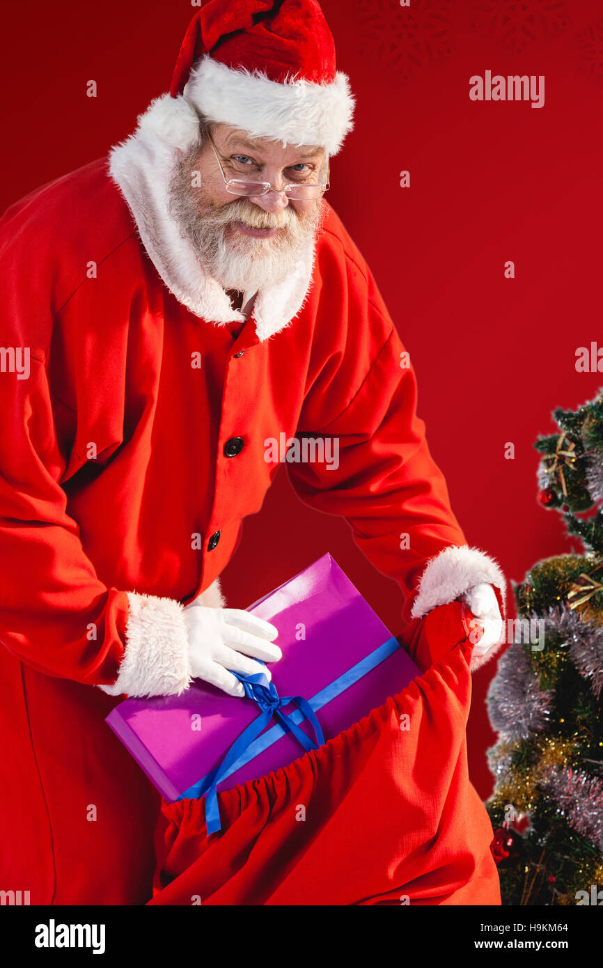 Composite image of santa claus putting christmas presents in christmas bag Stock Photo