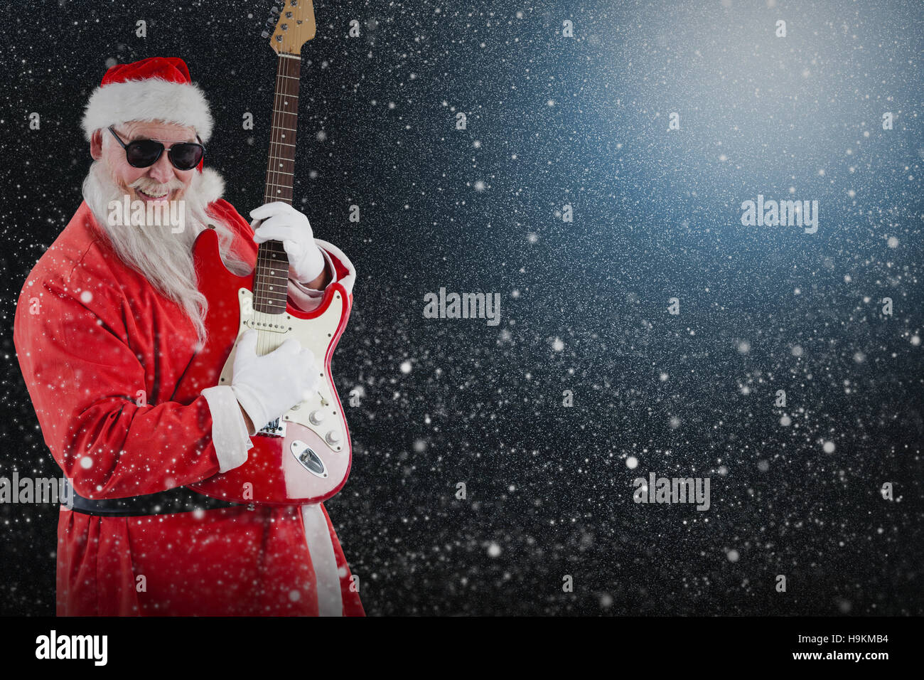 Composite image of smiling santa claus playing a guitar Stock Photo