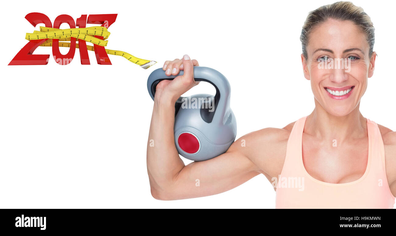 3D Composite image of happy female crossfitter lifting kettlebells looking at camera Stock Photo
