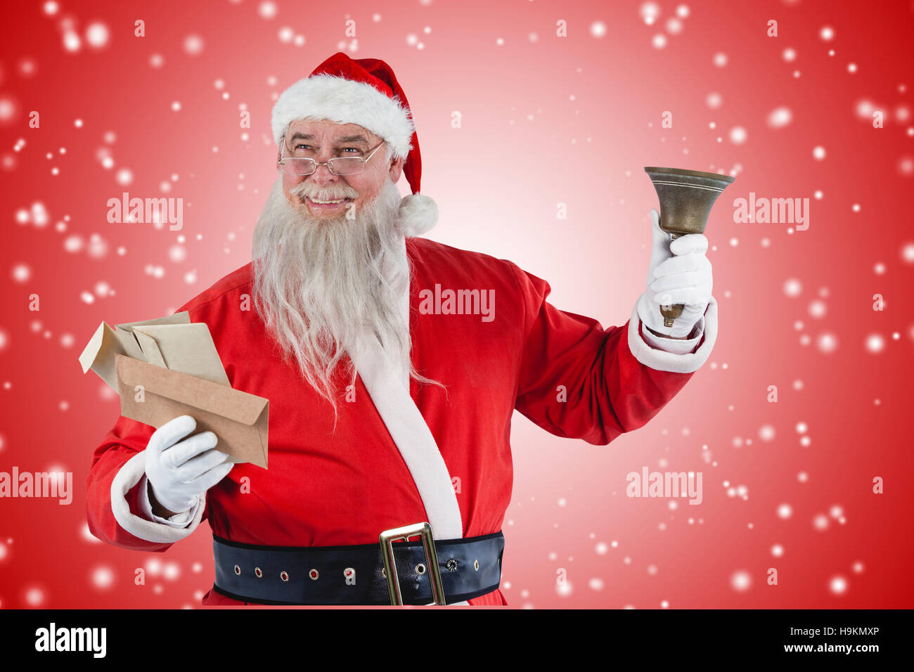 Composite image of santa claus holding envelope and bell Stock Photo