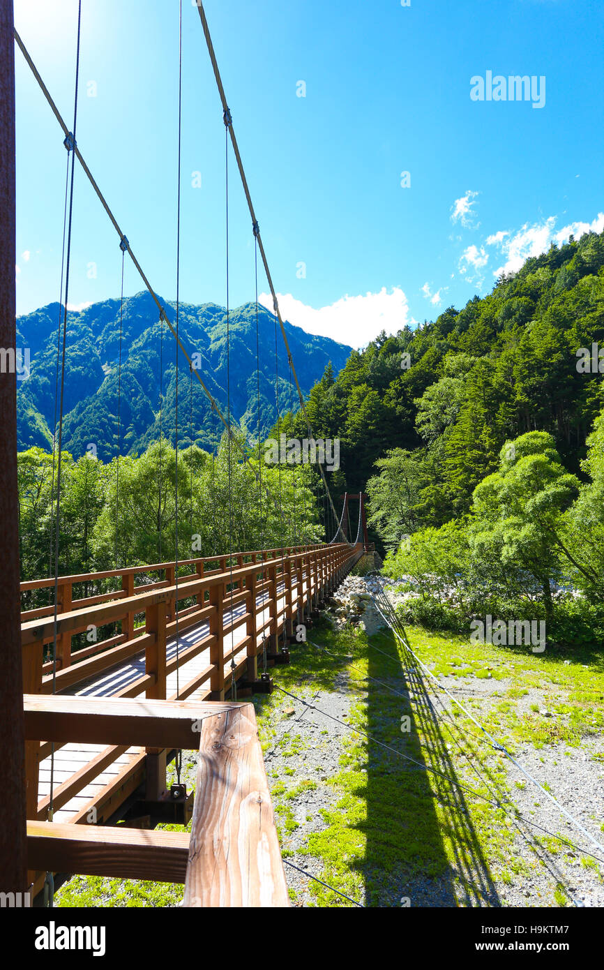 Dry riverbed under Shinmura Bashi Bridge side view surrounded by mountain landscape during sunny summer day in Kamikochi Stock Photo