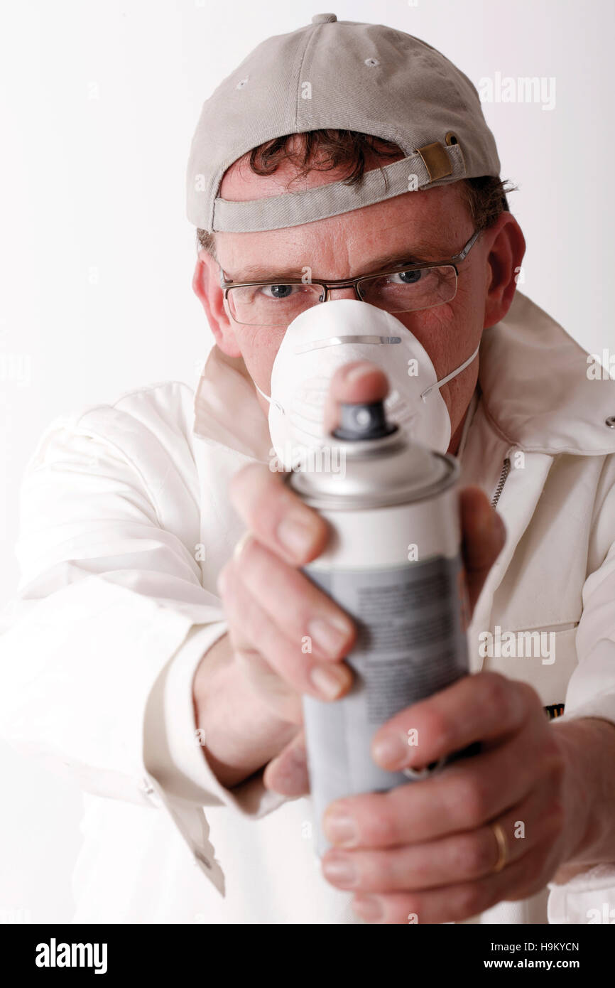 Workman, with breathing protection, holding a can of spray paint Stock