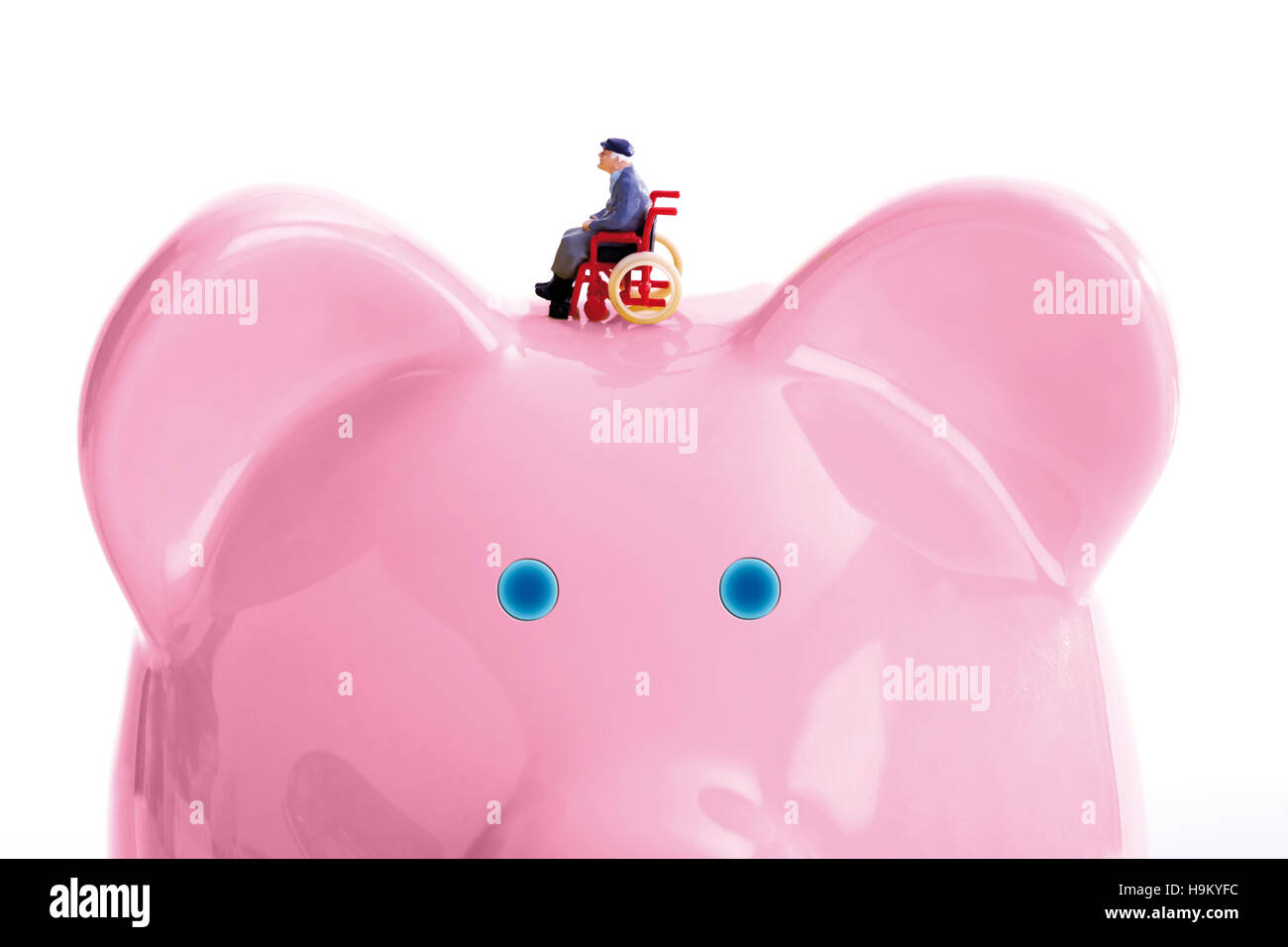 Figurine of a man in a wheelchair on a pink biggy bank Stock Photo