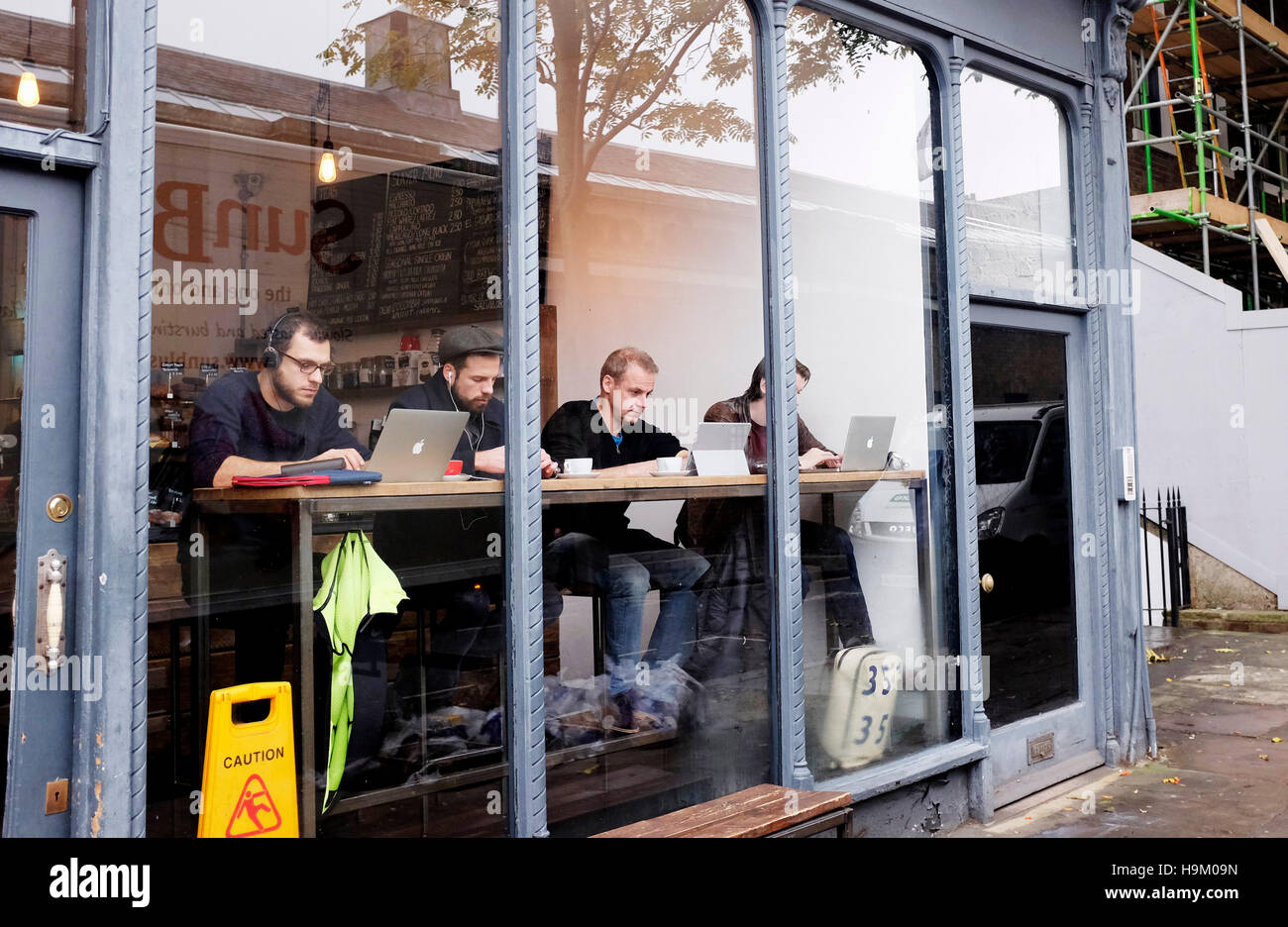 Islington London UK - Men at their computers in window of a coffee shop in Islington High Street Stock Photo