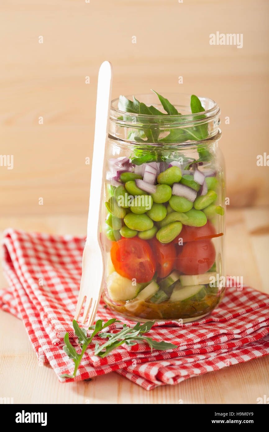 healthy vegetable salad in mason jar tomato, cucumber, soybean, onion