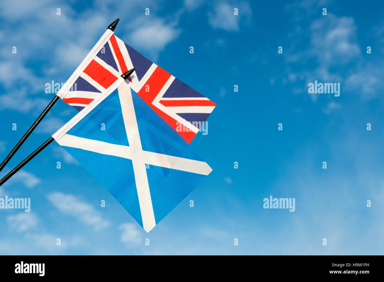 Scottish and UK Union Jack flags flying together in bright blue sky Stock Photo