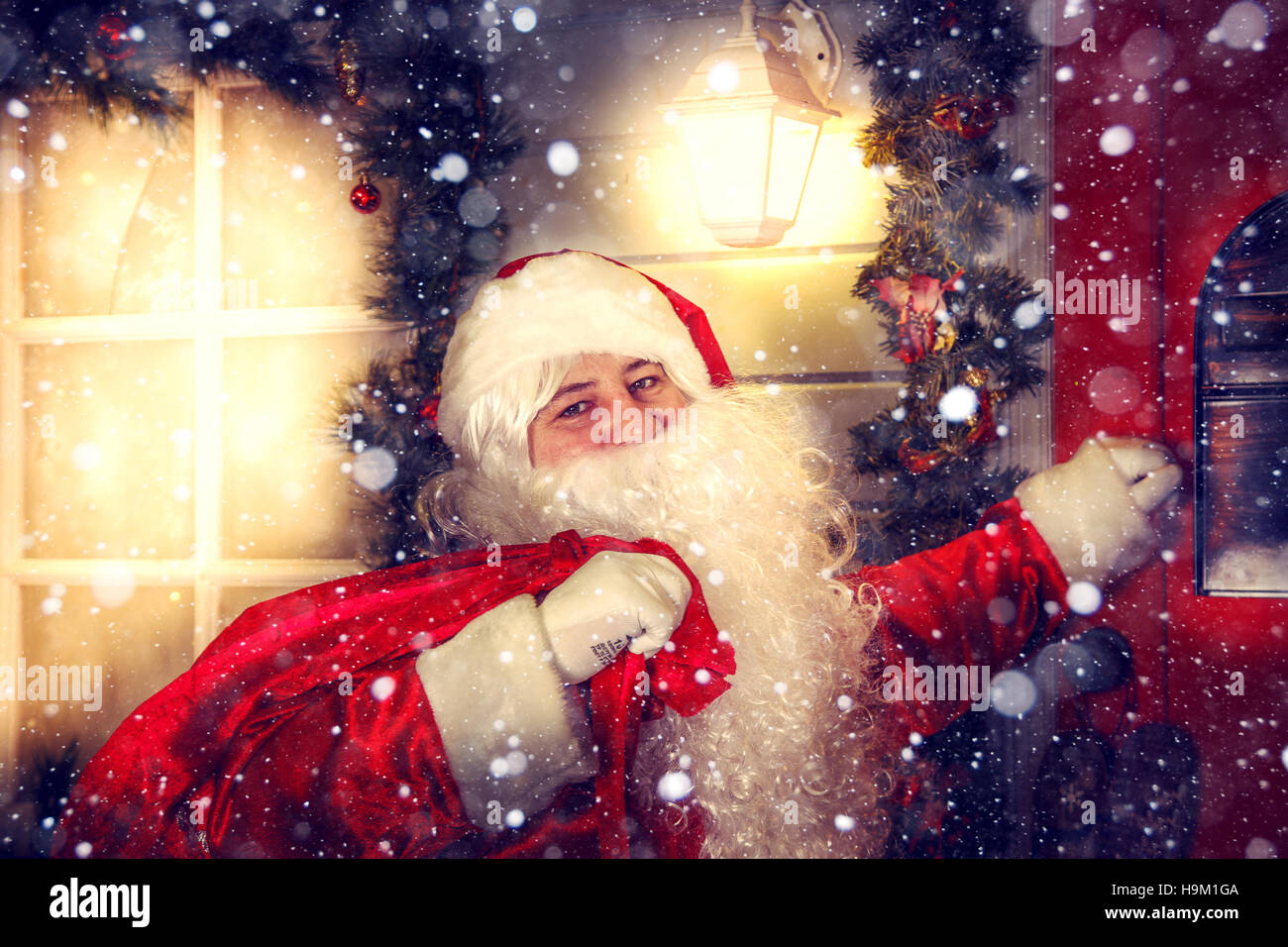 The real Santa Claus. Santa knocks on the door. Christmas night. Stock Photo