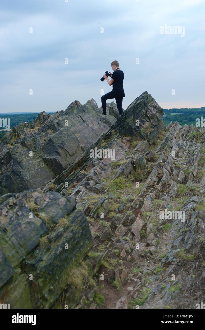 A young photographer looks at the images on his digital camera on a mountaintop. Stock Photo