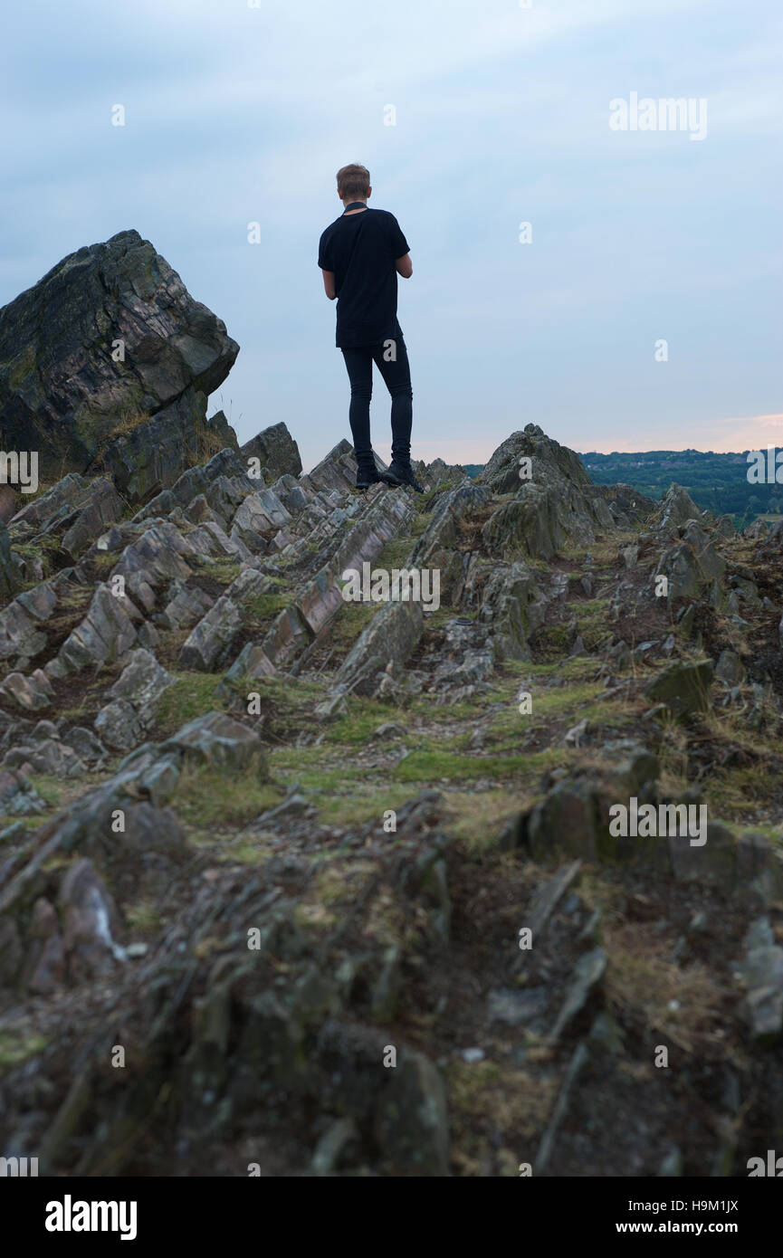 A young teenager stand on a rocky ridge. Stock Photo