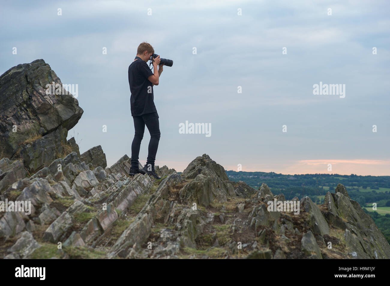 A young photographer takes a photo on a rocky ridge Stock Photo Alamy
