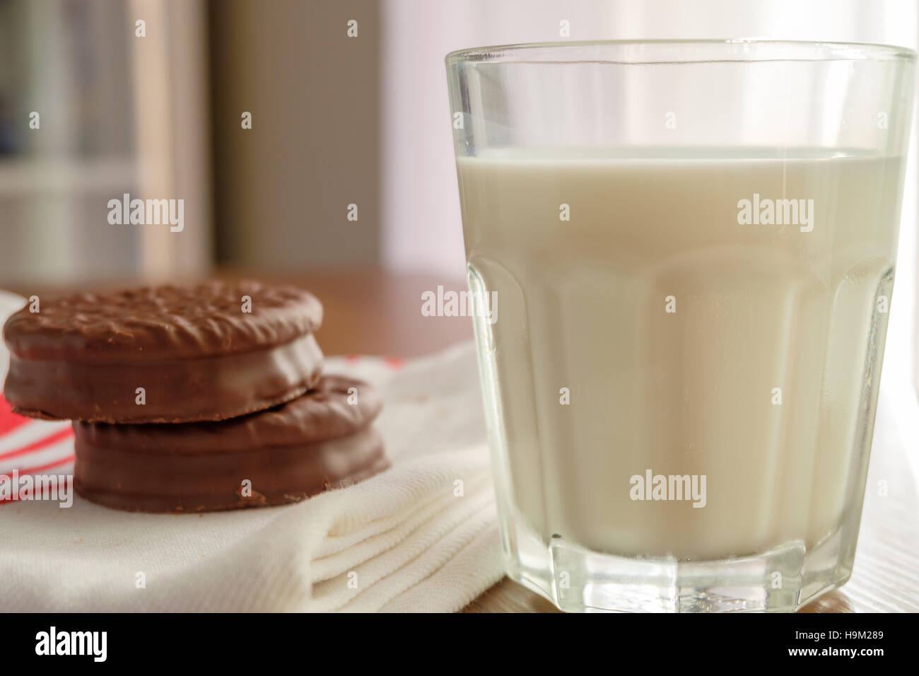Chocolate cookies on white linen napkin and a glass of milk on wooden, selective focus Stock Photo