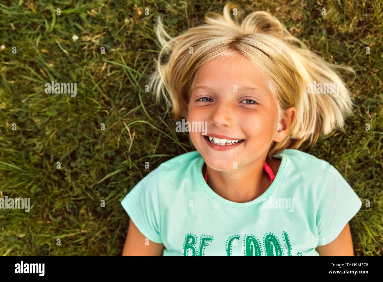 Portrait of smiling blond girl lying on a meadow Stock Photo - Alamy