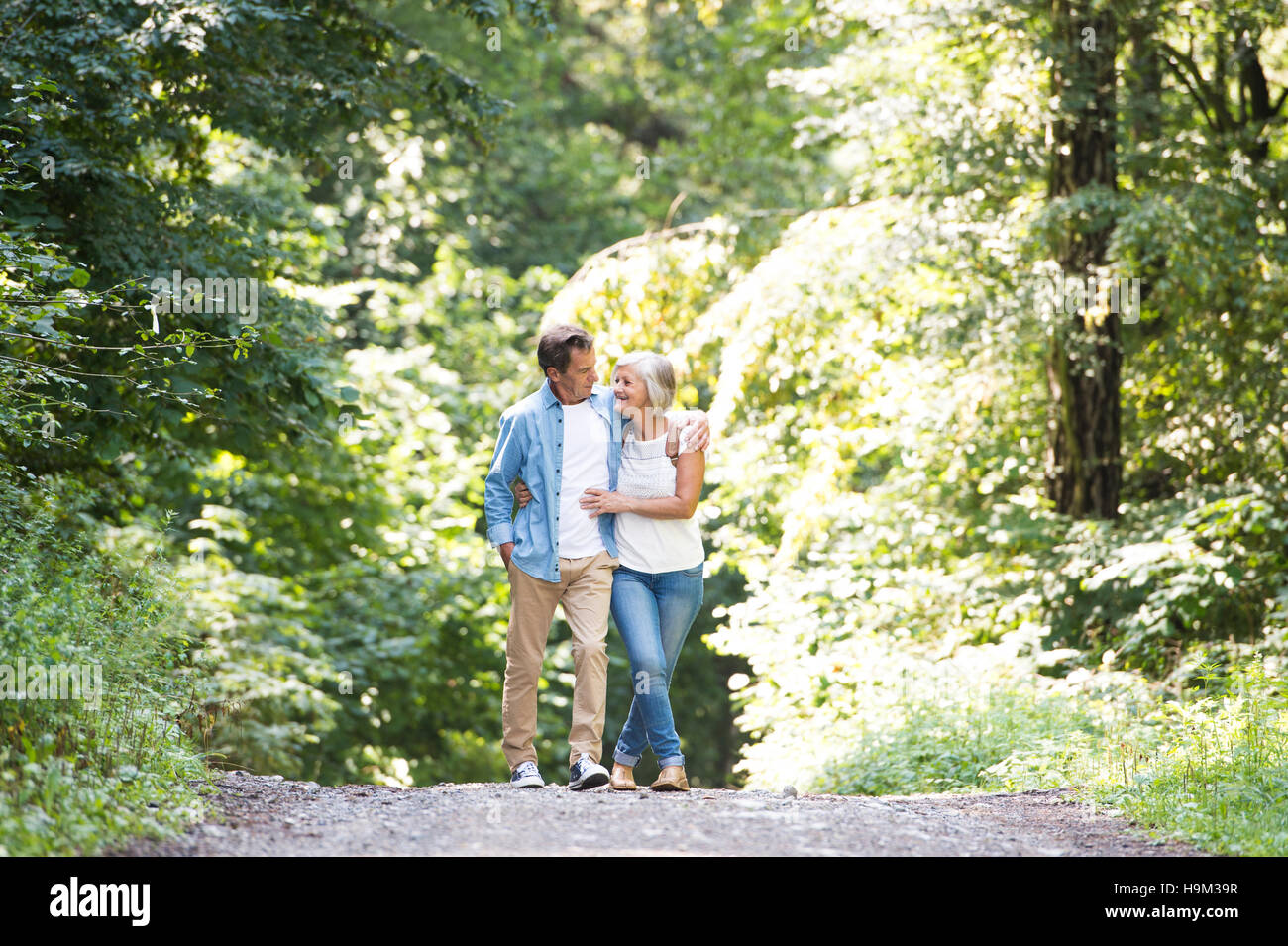 Happy senior couple walking arm in arm in the woods Stock Photo - Alamy