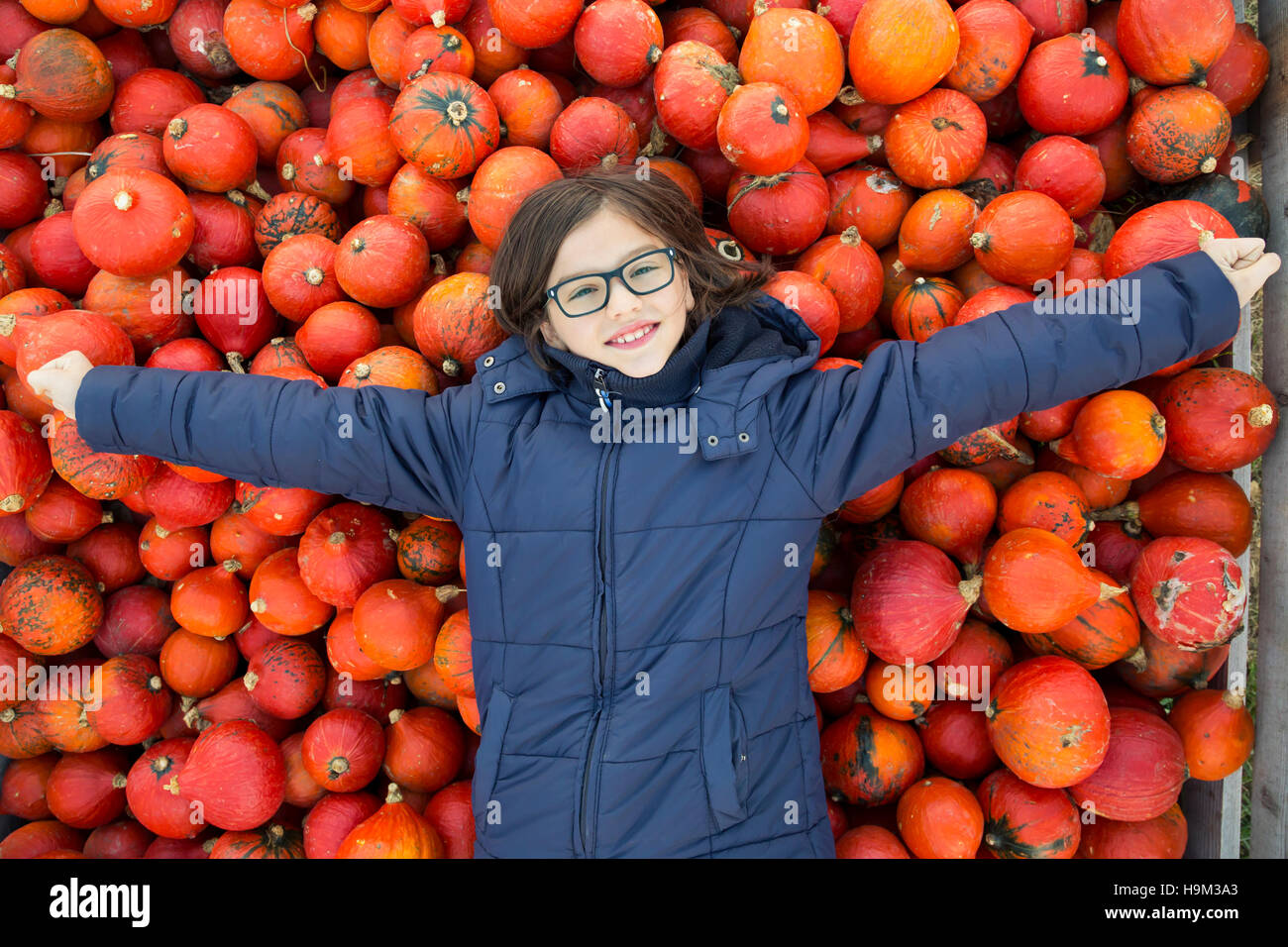 Portrait os smiling girl lying on pile of Hokkaido pumpkins Stock Photo ...