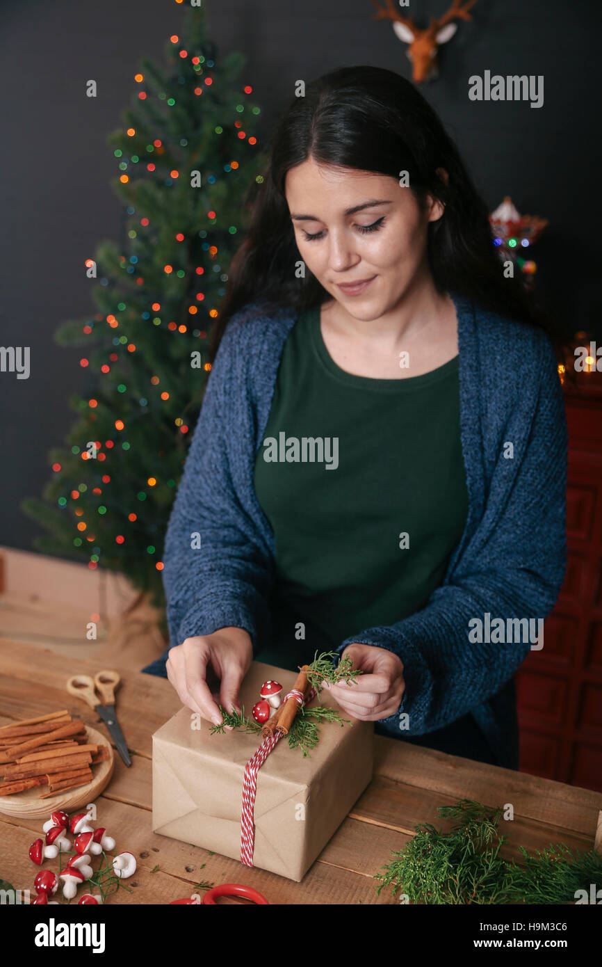 Young woman decorating Christmas present Stock Photo