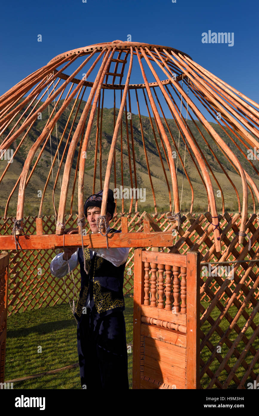 Man in traditional clothes tying the wood frame of a Yurt in Saty Kazakhstan Stock Photo