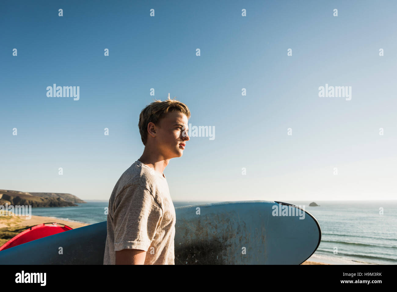 Teenage boy with surfboard looking to the sea Stock Photo