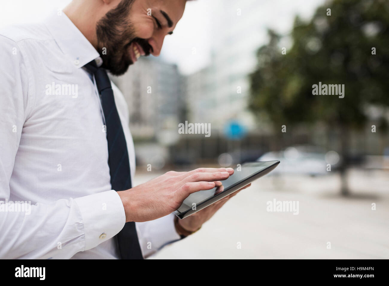 Smiling businessman using tablet on street Stock Photo - Alamy