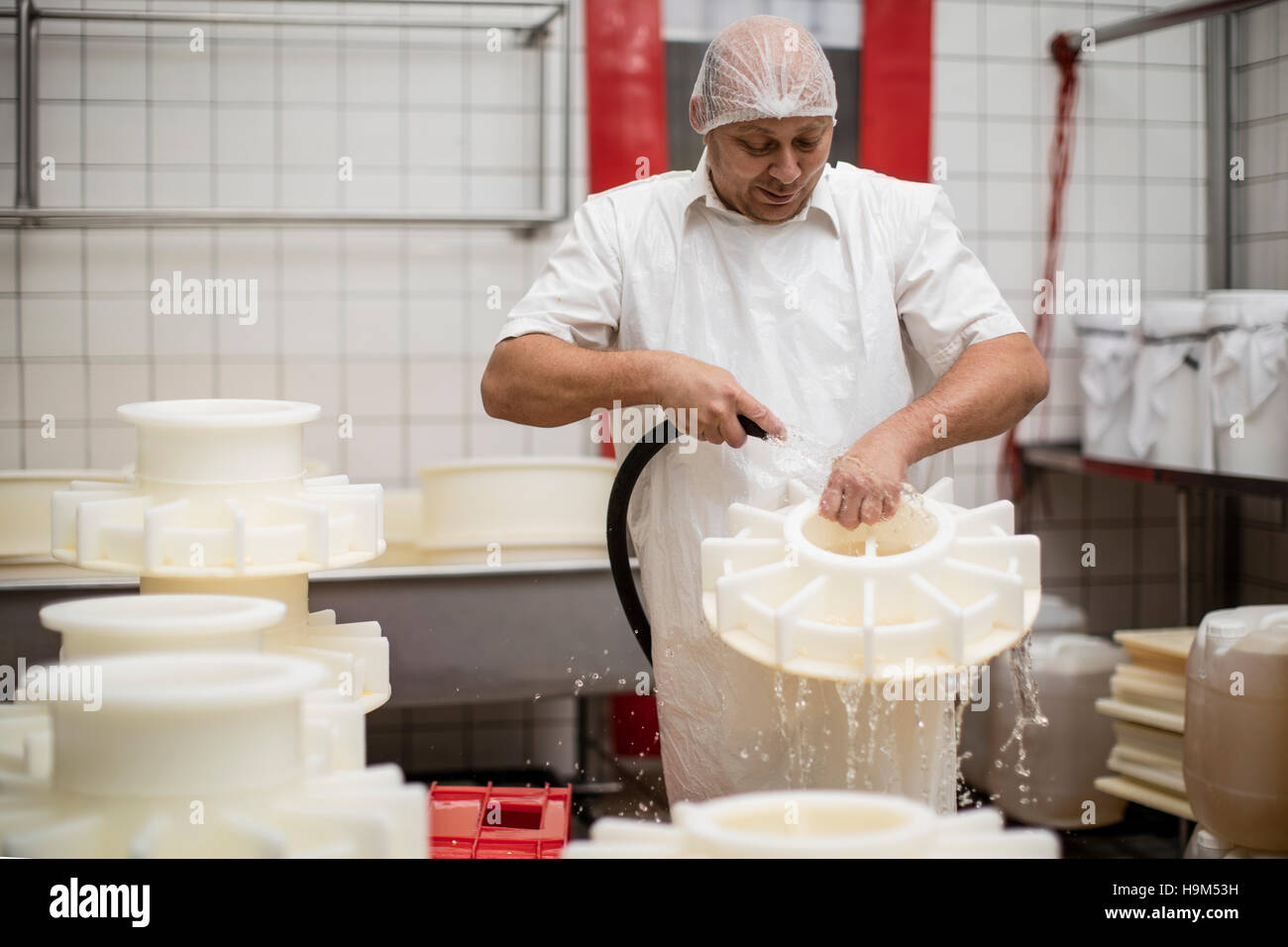 Cheese factory worker cleaning containers with hose Stock Photo Alamy