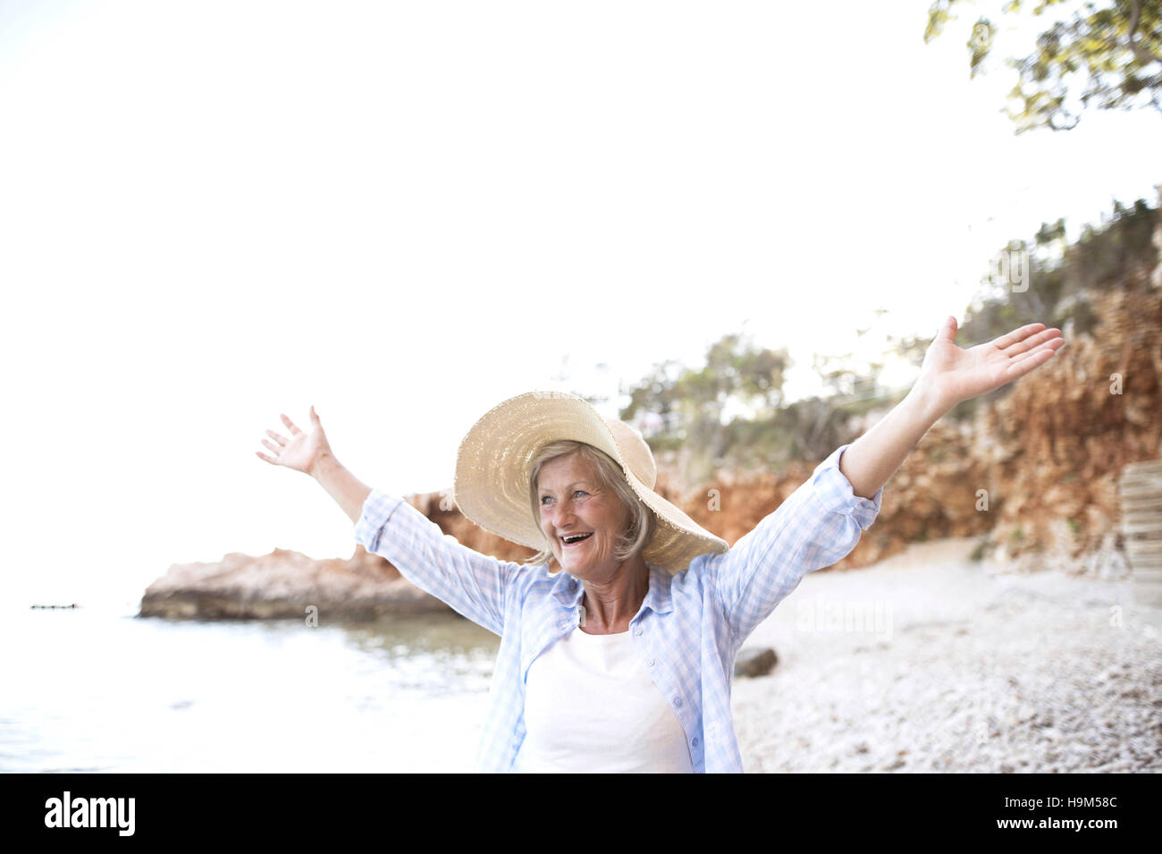 Happy mature woman wearing straw hat on the beach Stock Photo - Alamy
