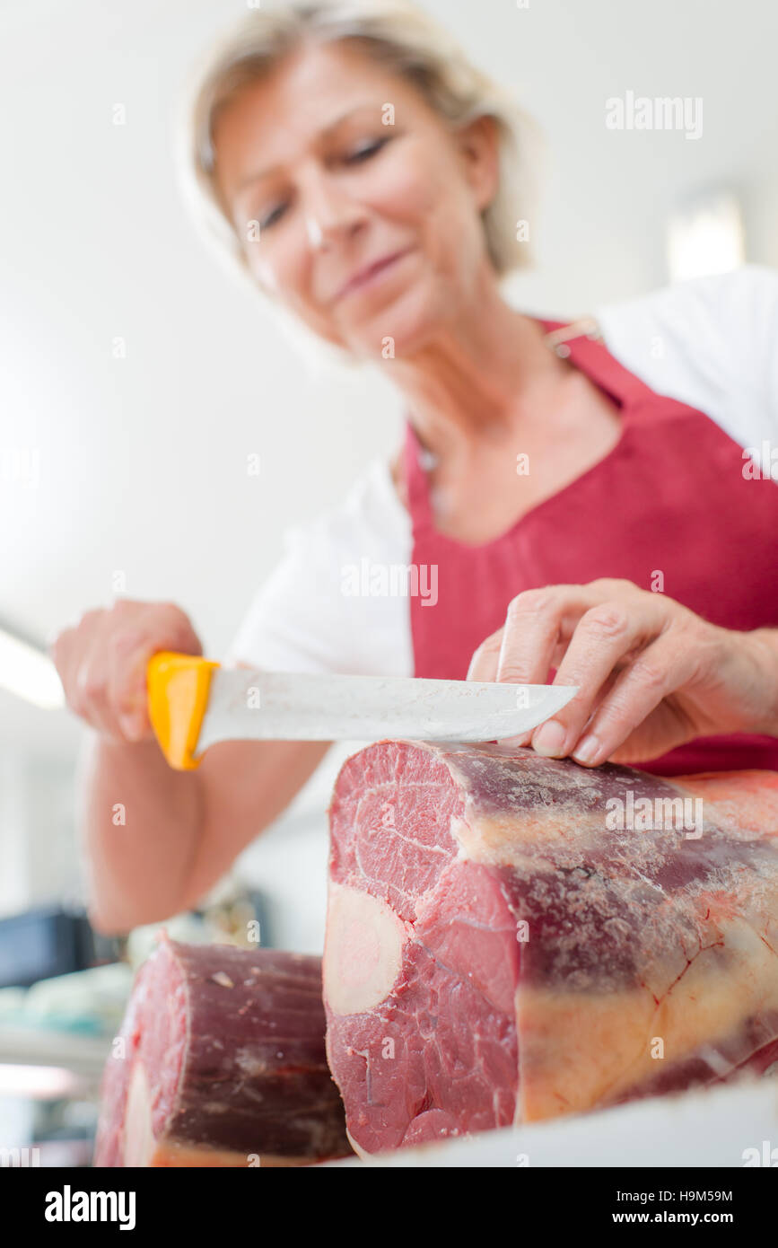 Female butcher slicing some beef Stock Photo